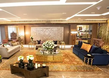 Living room with a spacious layout with modern light ceiling, elegant floral arrangements, and a grand table set-up at DLF king's court apartment.