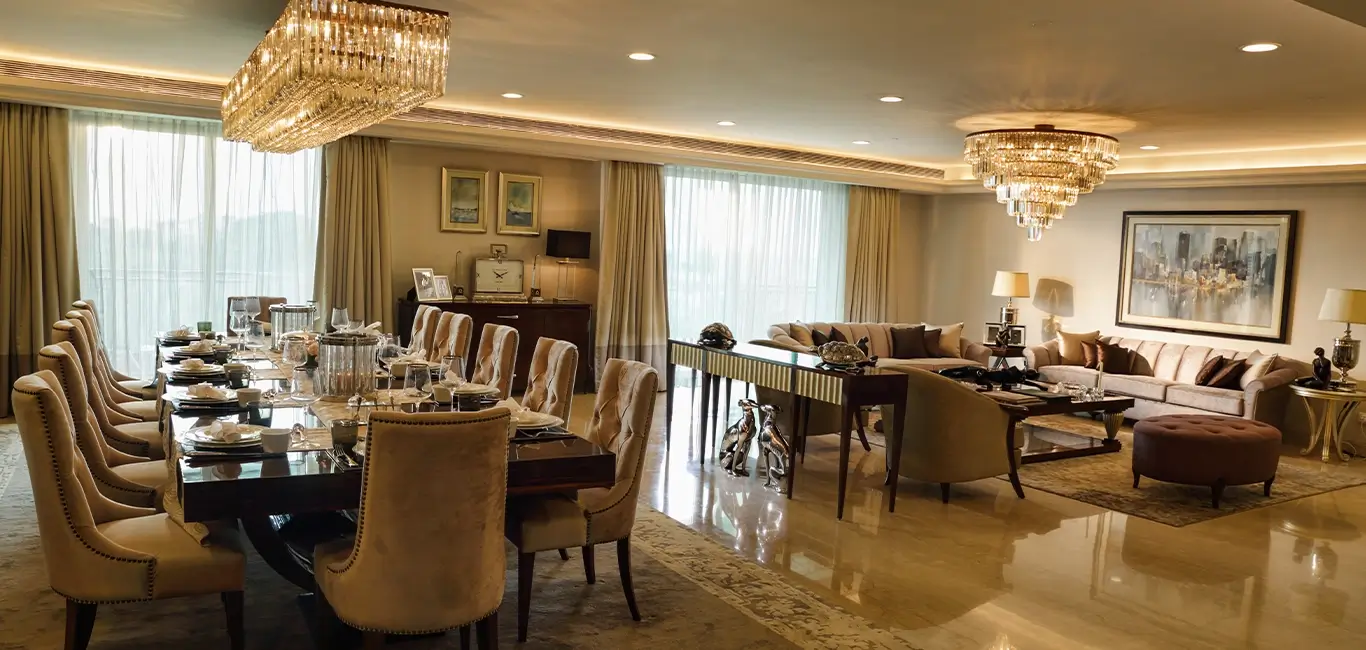 Luxurious dining area with spacious and elegant design. Attached living room featuring a plush sofa, chandeliers and beautiful flower arrangement.