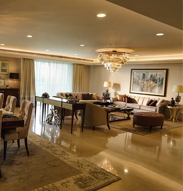 Luxurious dining area with spacious and elegant design. Attached living room featuring a plush sofa, chandeliers and beautiful flower arrangement.